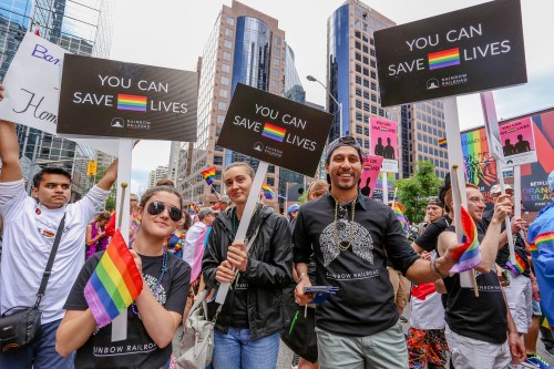 TORONTO, CANADA - JUNE 25 2017 RAINBOW RAILROAD marches with YOU CAN SAVE LIVES signs at 2017 Toronto Pride Parade